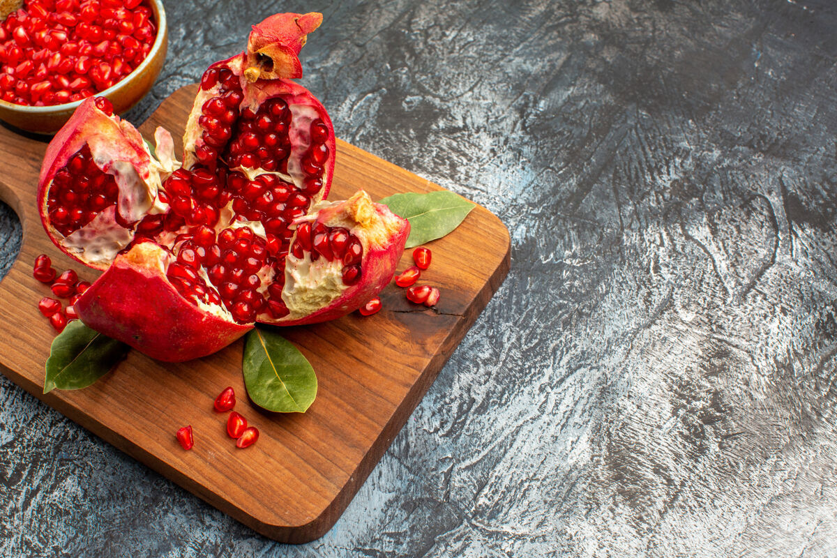 新鲜正面图石榴片新鲜的红色水果放在深色的桌子上红色的新鲜浆果美食生的浆果