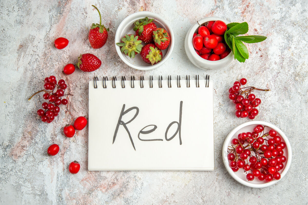 成熟顶视红色水果与红色书写记事本上的白色桌子浆果红色水果灌木葡萄干记事本