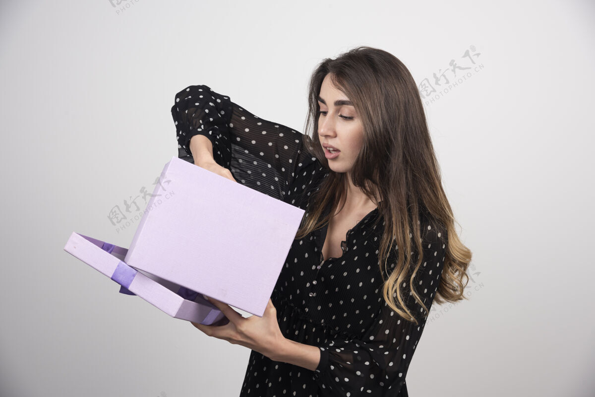 模特年轻的女人把手放进一个紫色的礼盒里年轻人女孩姿势