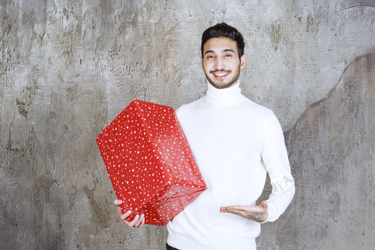 礼盒一个穿白毛衣的男人手里拿着一个上面有白点的红色礼盒人男性年轻