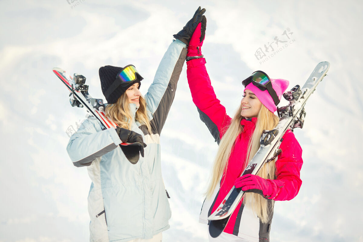 二女孩们在雪地里滑雪 享受拍照的乐趣 在山上度过时光休闲女人粉色