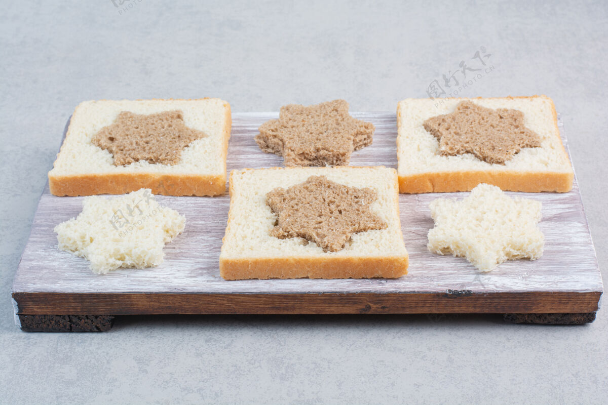 小吃木盘上星形和方形的黑白面包片谷类糕点形状