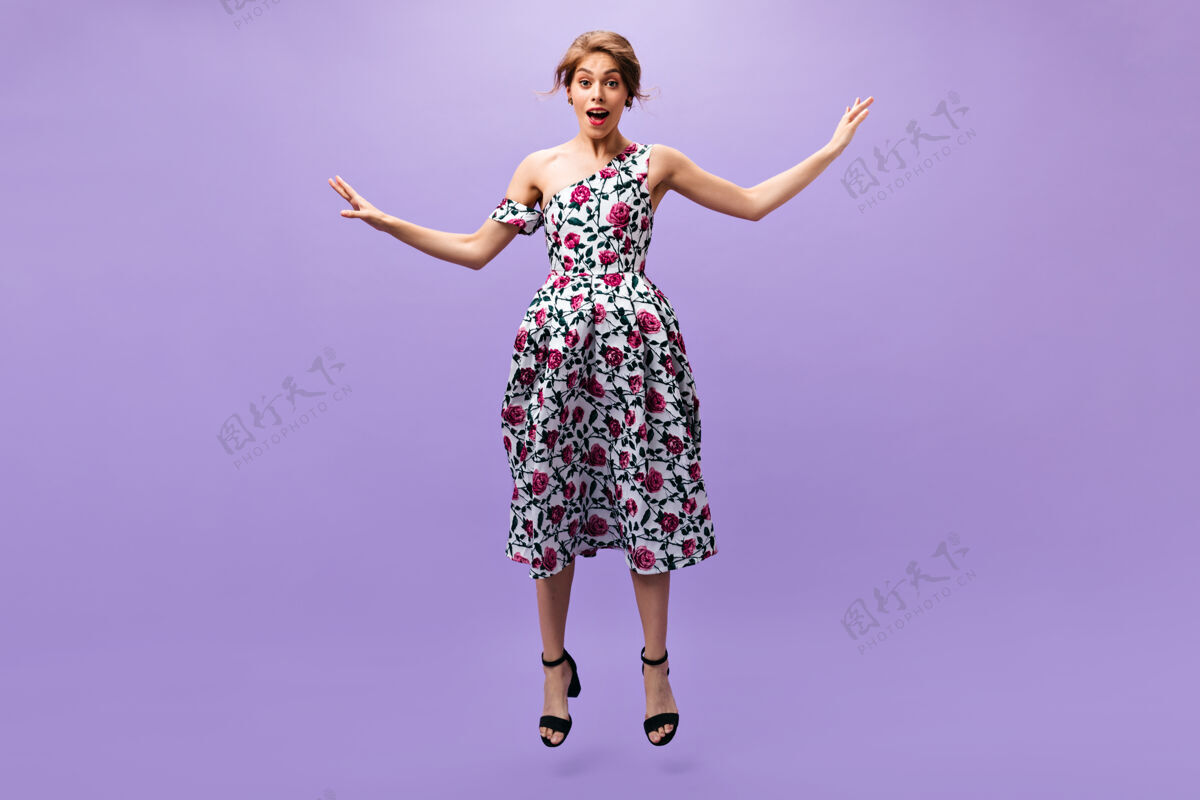 头发身着迷笛裙的女士在紫色背景上跳跃穿着五颜六色时尚服装的漂亮年轻女子在孤立的背景上摆姿势时尚紫色女孩