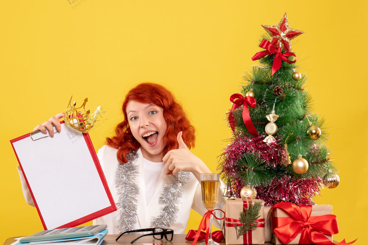插花前视图女医生拿着圣诞树周围的文件说明和礼物节日安排周围