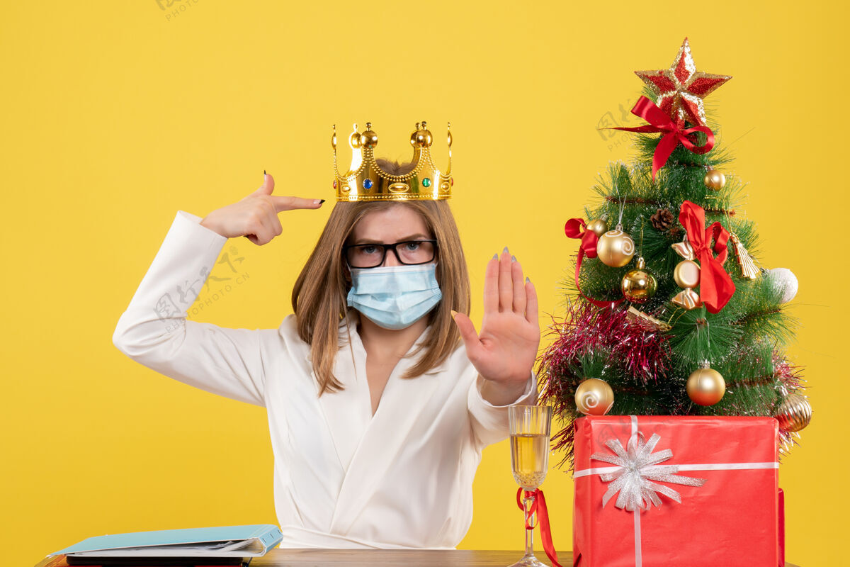 圣诞节正面图：戴着无菌面罩戴着皇冠的女医生病毒消毒人
