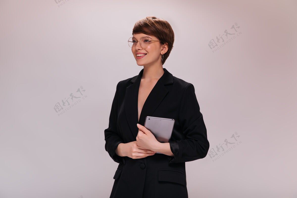 肖像身着黑色西装的女商人手持电脑平板电脑身着黑色夹克的短发员工在与世隔绝的背景下灿烂地微笑着女士套装年轻
