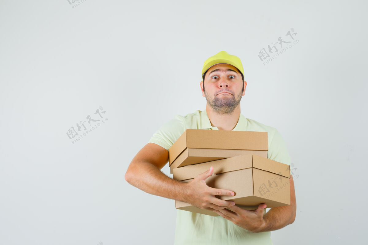 胡须戴着t恤帽拿着沉重纸板箱的年轻人抱着帽子沉重