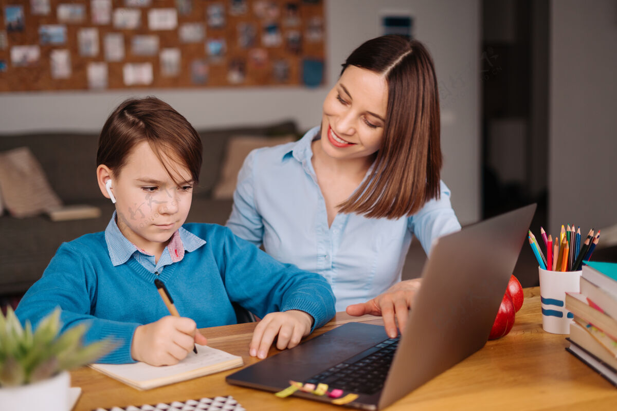 孩子一个未成年男孩用笔记本电脑和他妈妈旁边的老师打视频电话洋葱在线教育学龄前儿童