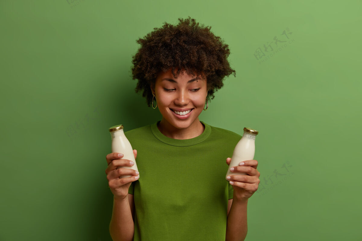 正餐健康 饮食和营养概念积极的黑皮肤年轻女子摆姿势与有机素食非日记牛奶 无乳糖饮料 微笑愉快 穿着绿色t恤 在室内摆姿势卷曲健身女士