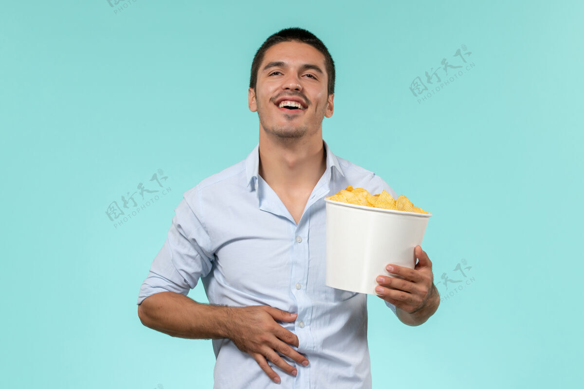 男人前视图年轻人拿着土豆cips在蓝色的地板上孤独的遥远的男性电影院视图土豆电影院