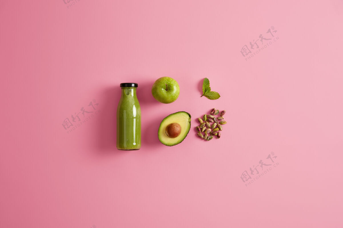 平板健康的绿色冰沙 由多汁的苹果 鳄梨 开心果和薄荷制成玫瑰色的背景为您平衡饮食的新鲜营养饮料准备清爽营养饮料的配料配料玻璃蔬菜