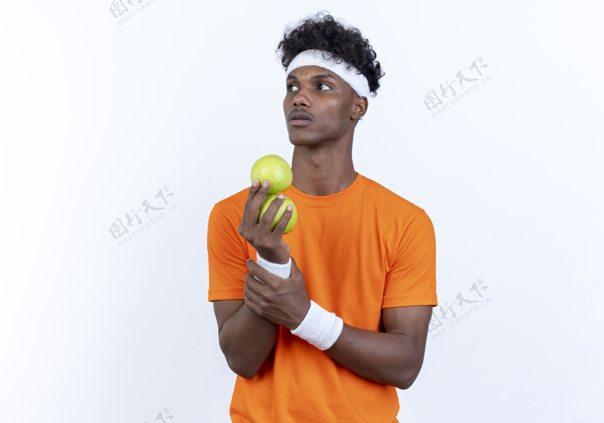 头带看着身边年轻的美国黑人运动男子戴着头带和腕带拿着苹果孤立的白色背景抱着苹果壁板