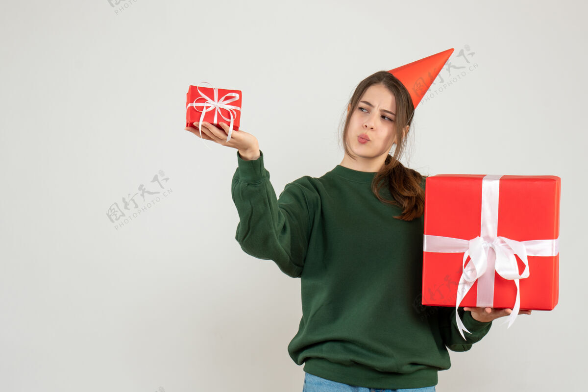 微笑前视图好奇的女孩与党帽比较她的圣诞礼物比较聚会帽子