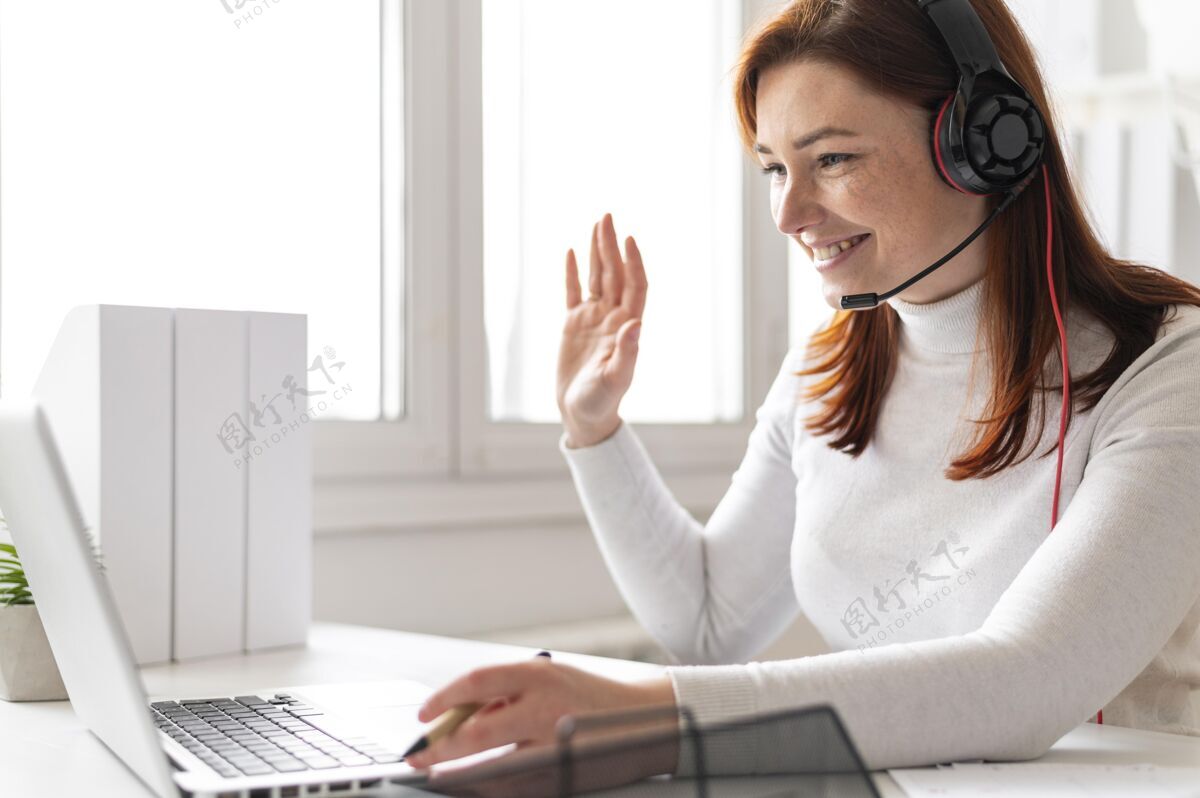 耳机工作中的女人正在笔记本电脑上进行视频通话模型办公桌女性