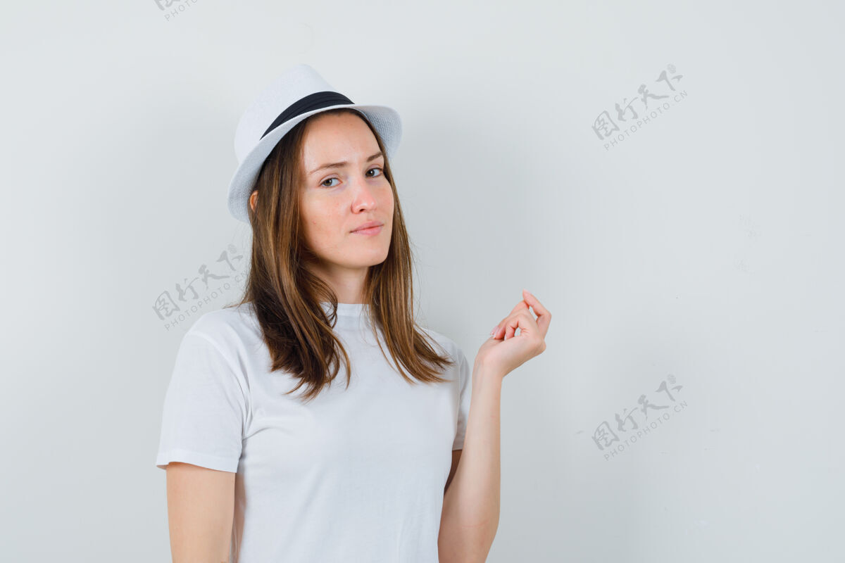积极戴着白色t恤帽子的年轻女士一边看着镜头一边思考 一边看起来很懂事人性化同时女士