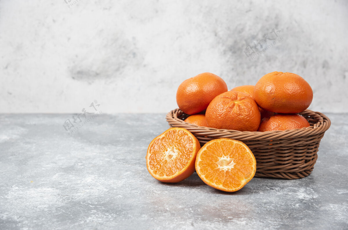 圆形石桌上摆满了柳条盒的多汁橙子提神柑橘热带