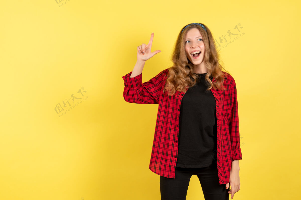 年轻女性正面图身着红色格子衬衫的年轻女性在黄色背景上微笑着摆姿势人类情感色彩模特儿姿势微笑格子