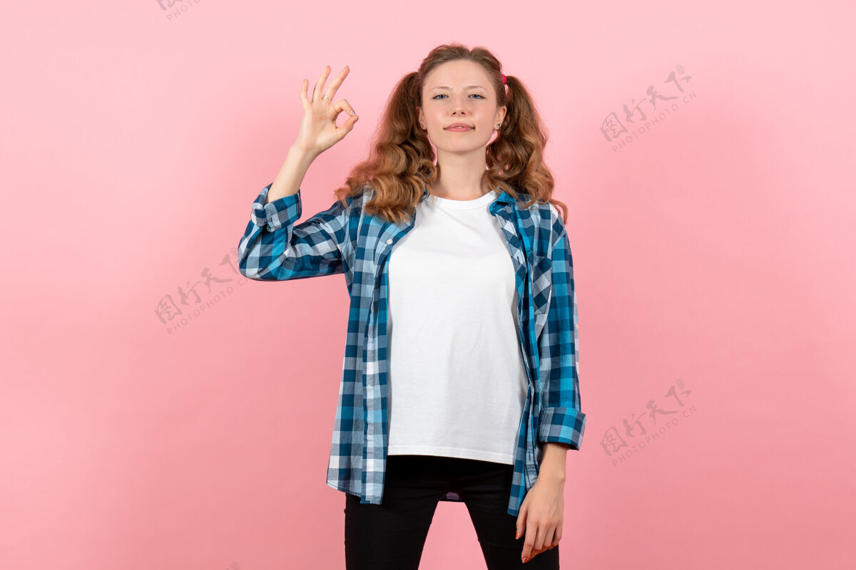 肖像正面图身着格子衬衫的年轻女性在粉色背景上摆姿势年轻女性情感模特儿颜色格子孩子年轻