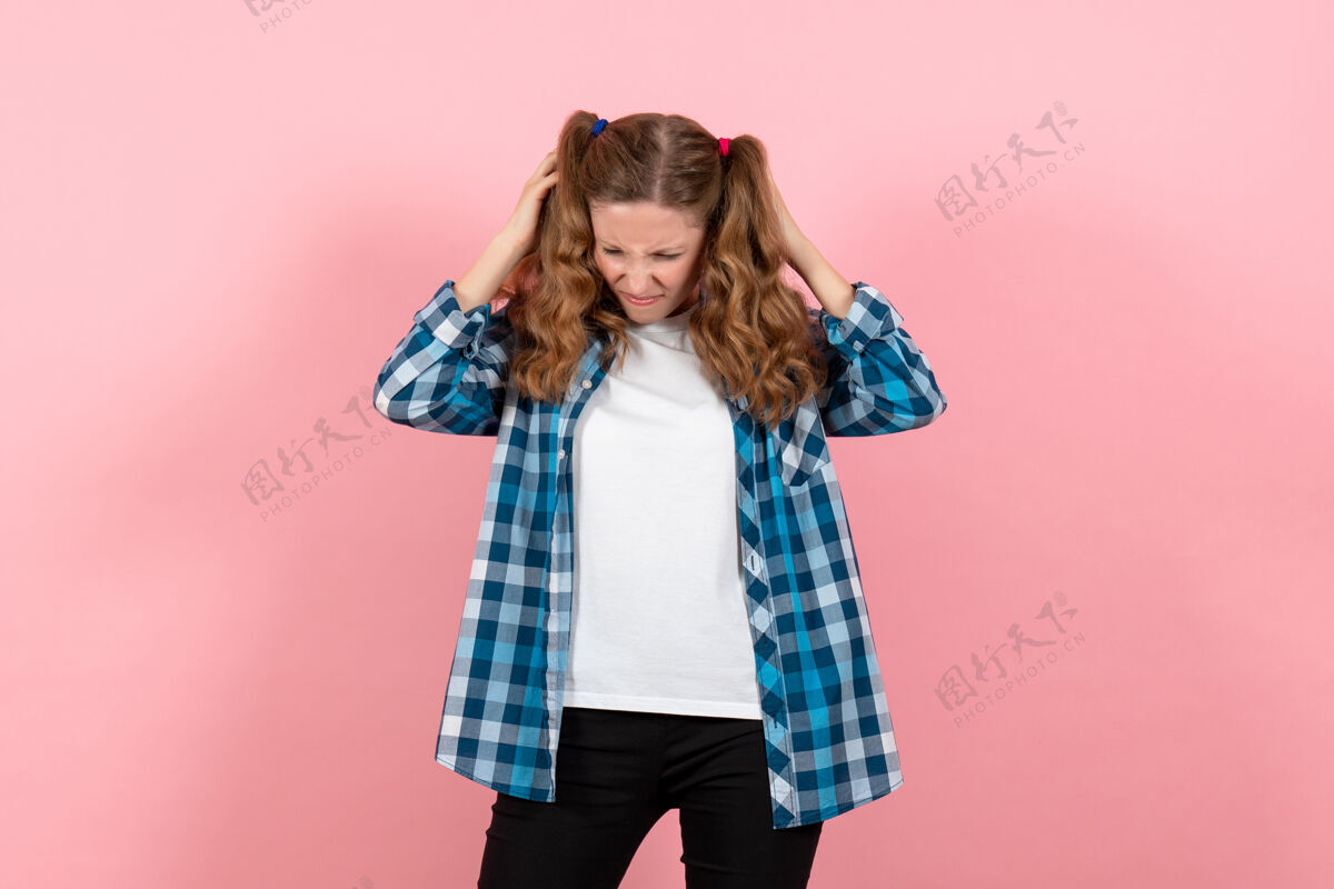 情感正面图身着蓝色格子衬衫的年轻女性在粉色背景上摆姿势童女青年情感模特时尚年轻女性漂亮肖像