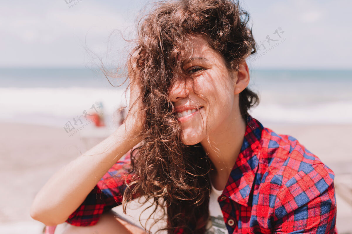 人暑假快乐快乐快乐的女人 卷发飘飘坐在海边风海滩人