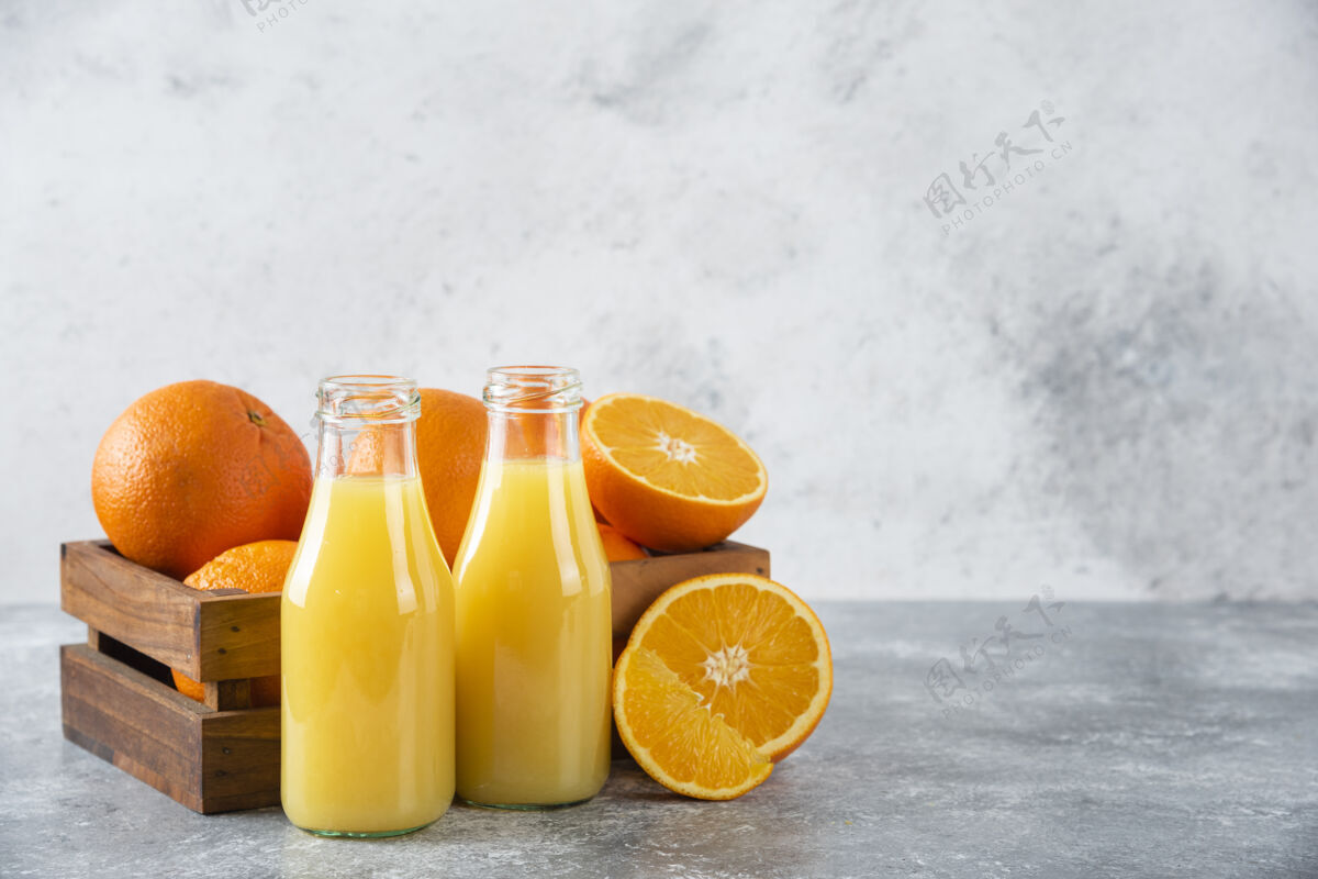 圆形石桌上放着一杯果汁和新鲜的橙子味道水果甜点