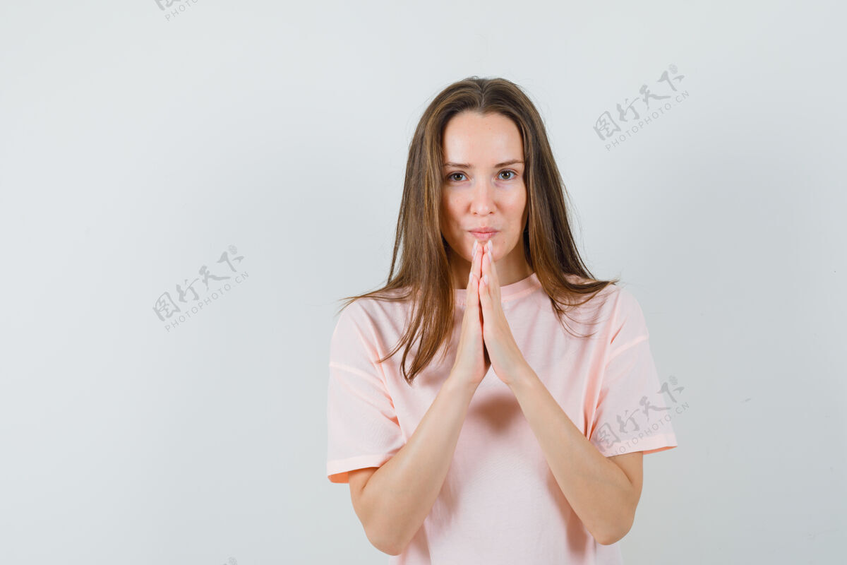 希望身穿粉色t恤的年轻女士手牵手祈祷 看上去充满希望时尚手兴奋