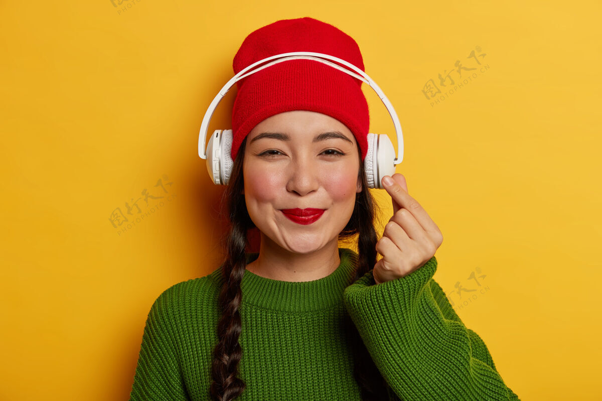 声音可爱的黑发女人 戴着红帽子 穿着绿色套头衫 听音乐满意旋律感情
