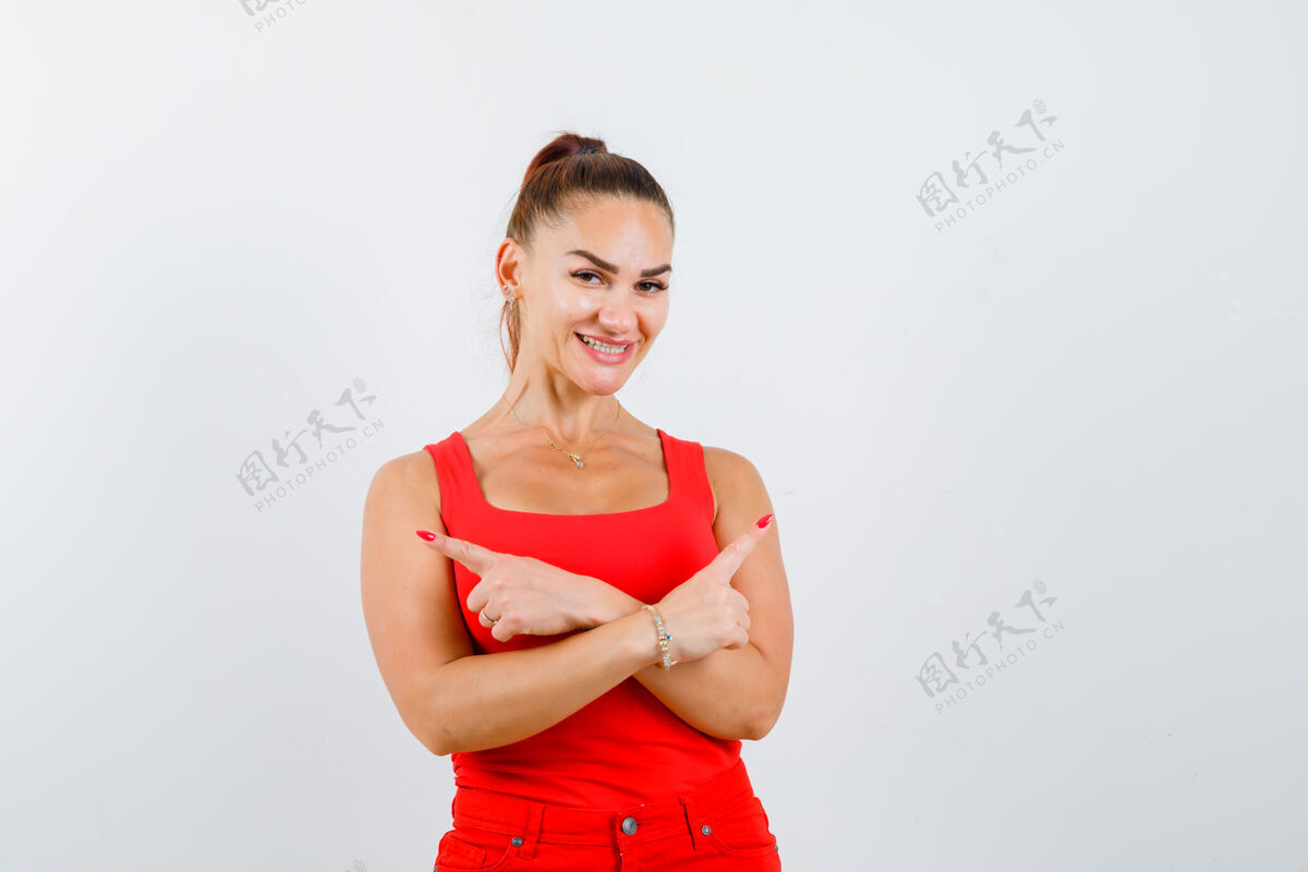 人年轻的女性指着两边的红色背心 裤子 看着很开心 前视漂亮时尚裤子