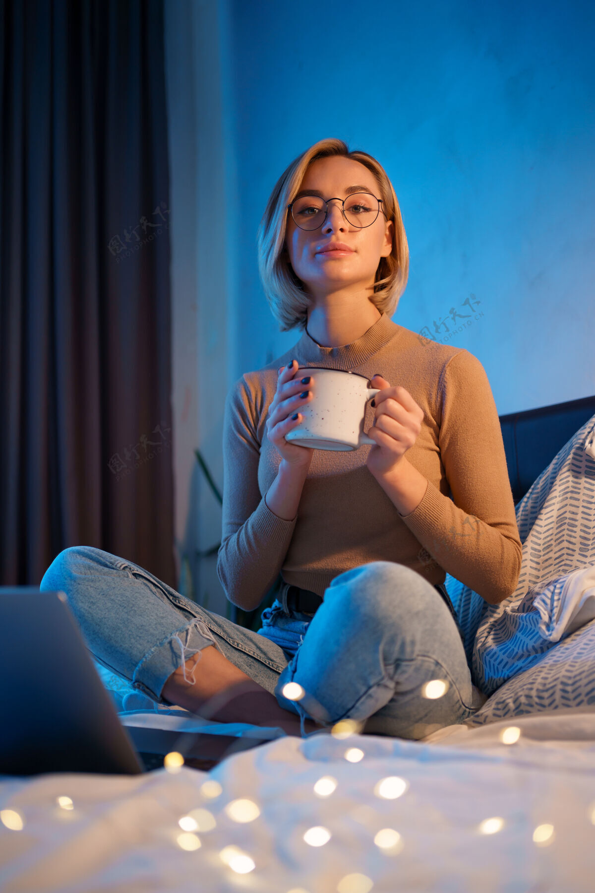 阅读女人在卧室里用笔记本电脑放松 喝一杯热咖啡或茶马克杯笔记本教育
