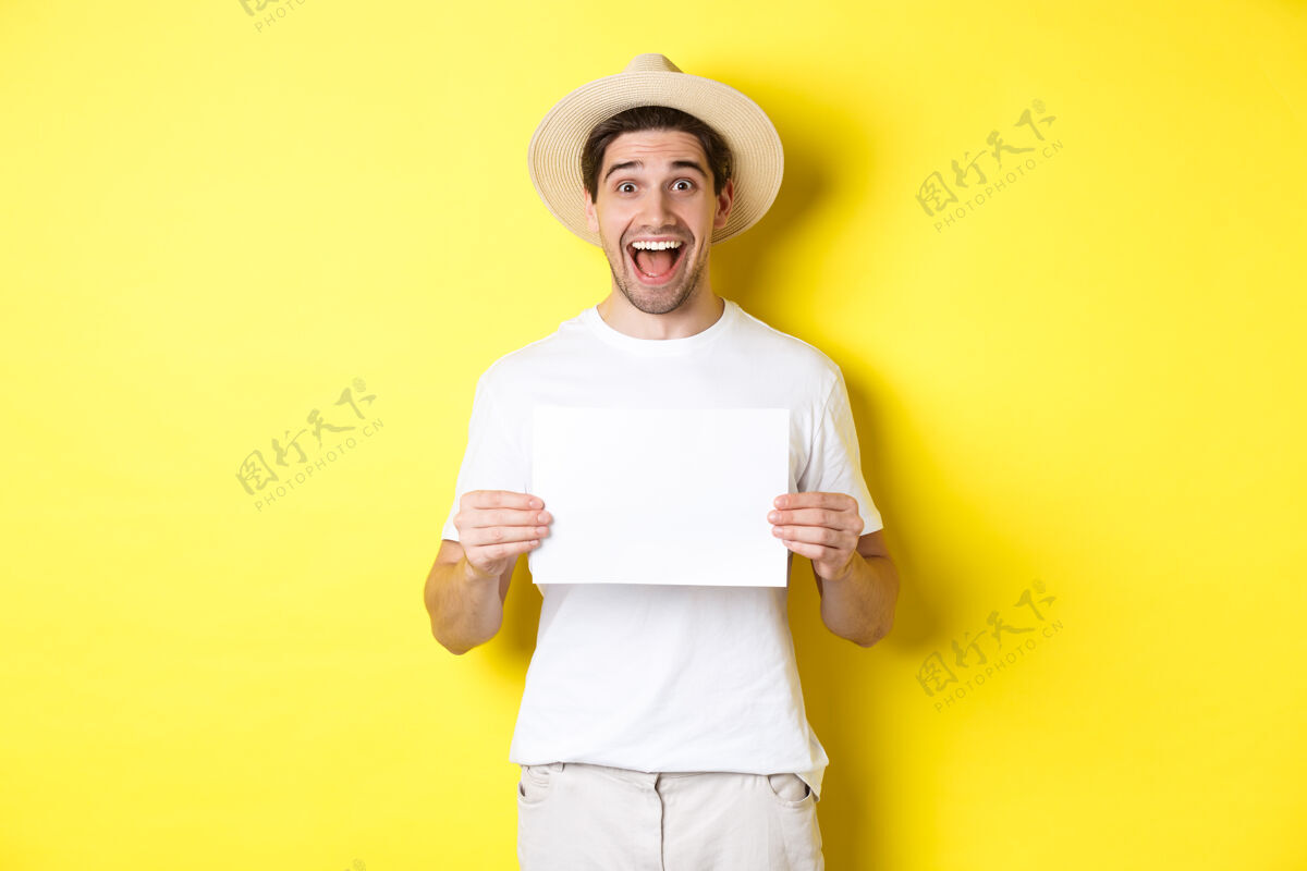 假日兴奋的游客在一张空白的纸上展示你的标志 面带惊奇的微笑 站在黄色的背景下黄色男人模特