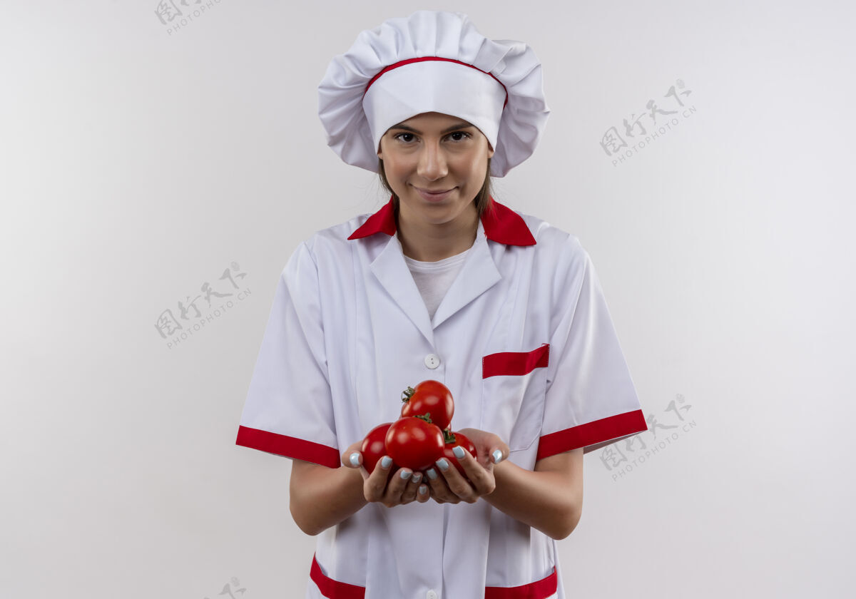 烹饪穿着厨师制服的年轻快乐的白人厨师女孩手上拿着西红柿 上面有白色的复印空间空间制服请