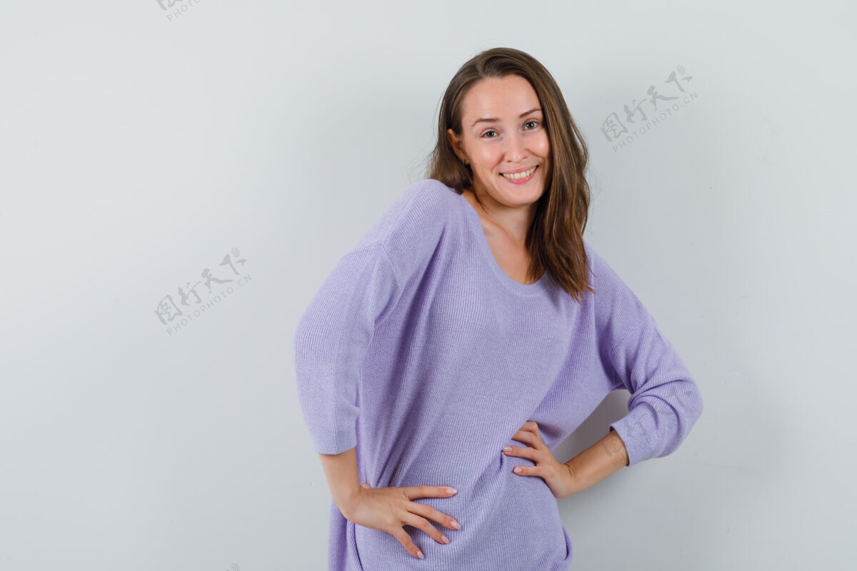 女士身穿淡紫色上衣的年轻女性 手放在腰上摆姿势 看起来很迷人漂亮腰部手