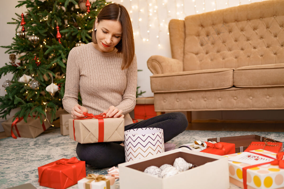 礼物女人坐在客厅里的衣柜上包装圣诞礼物桌子女人包装