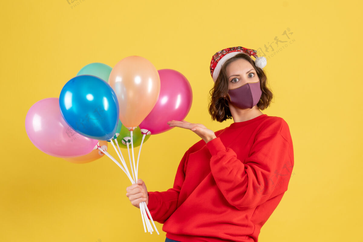 女人正面图：戴着黄色面具手持气球的年轻女子情感派对庆祝