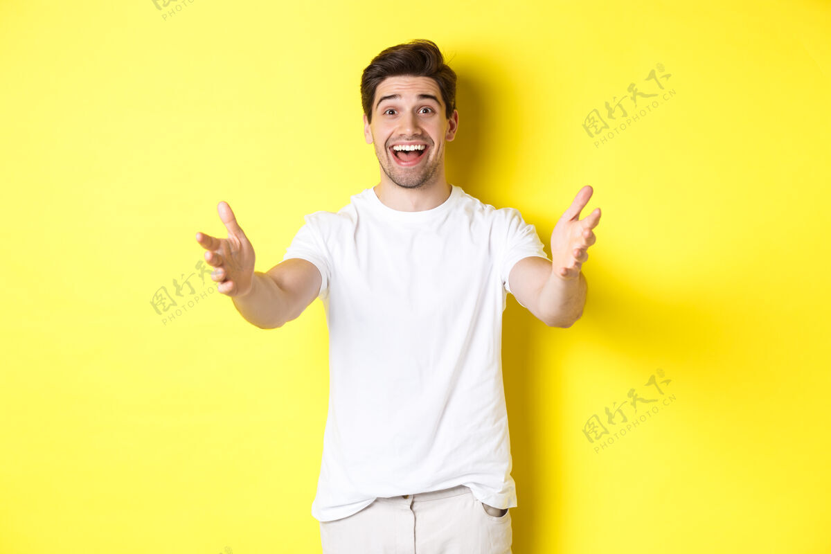 年轻兴奋的帅哥向前伸着手 伸手拥抱 接受礼物 站在黄色背景上表情工作室男人
