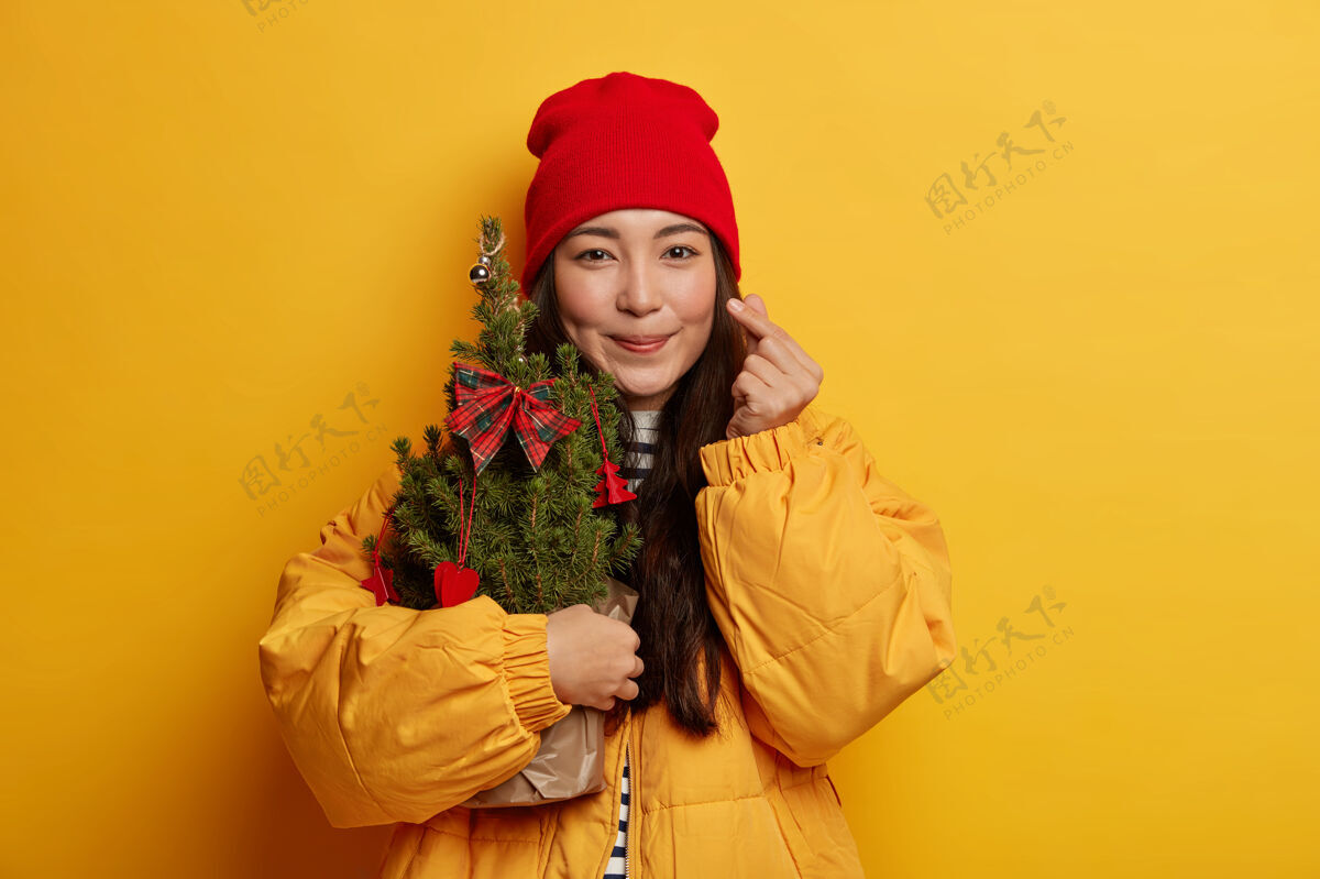 毛衣年轻漂亮的女人拿着圣诞装饰品携带温柔民族