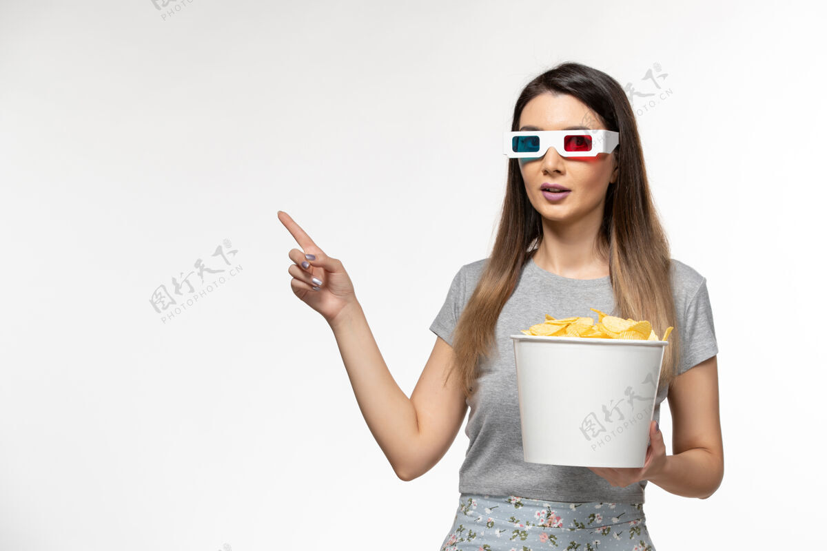 年轻的女性前视图年轻女性手持筹码 戴着d墨镜在白色地板上看电影电影院孤独的女性遥控器太阳镜地板看