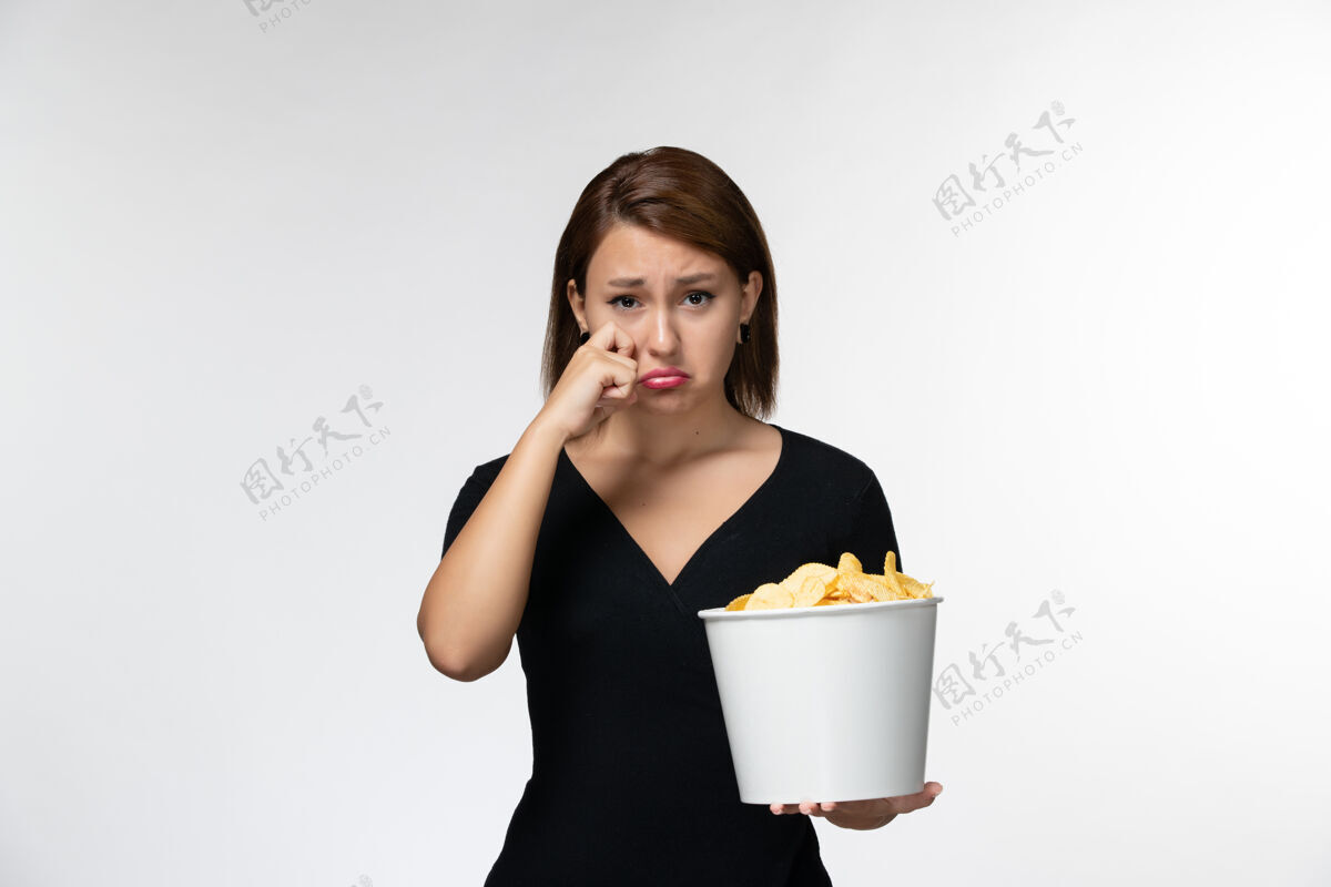 电影院正面图年轻的女性拿着篮子 拿着薯片看电影 在白色的表面哭泣笔记本电脑剧院电影
