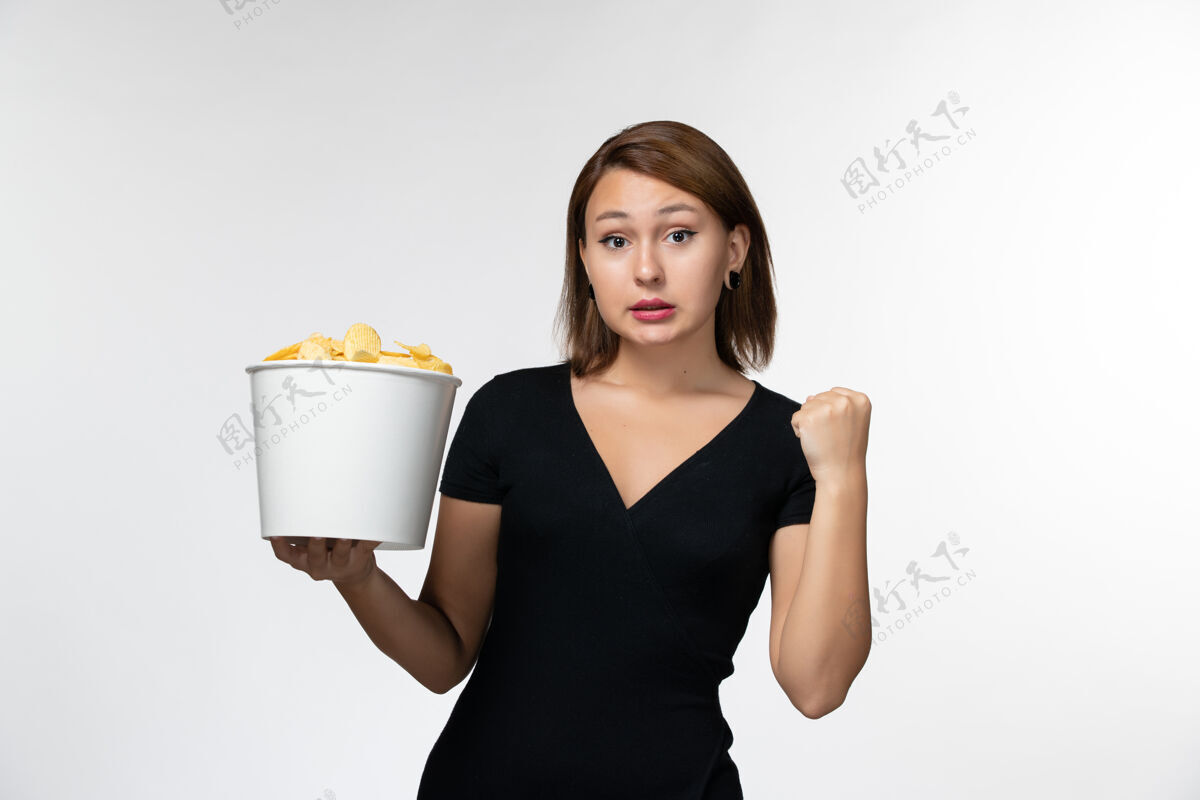 秘书正面图：年轻的女性拿着装满薯片的篮子 在白色的表面上欢呼雀跃篮子漂亮女士