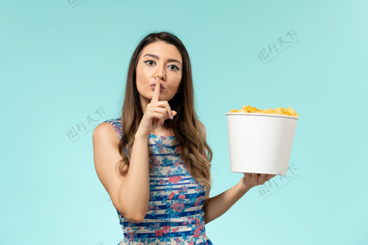 电影正面图：年轻的女性拿着篮子和薯片 在蓝色的水面上看电影前面女士电影