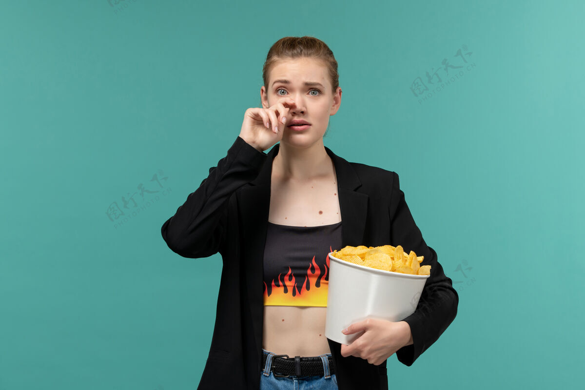 电影院正面图：年轻的女性拿着薯片在蓝色的桌子上看电影员工电影服务员