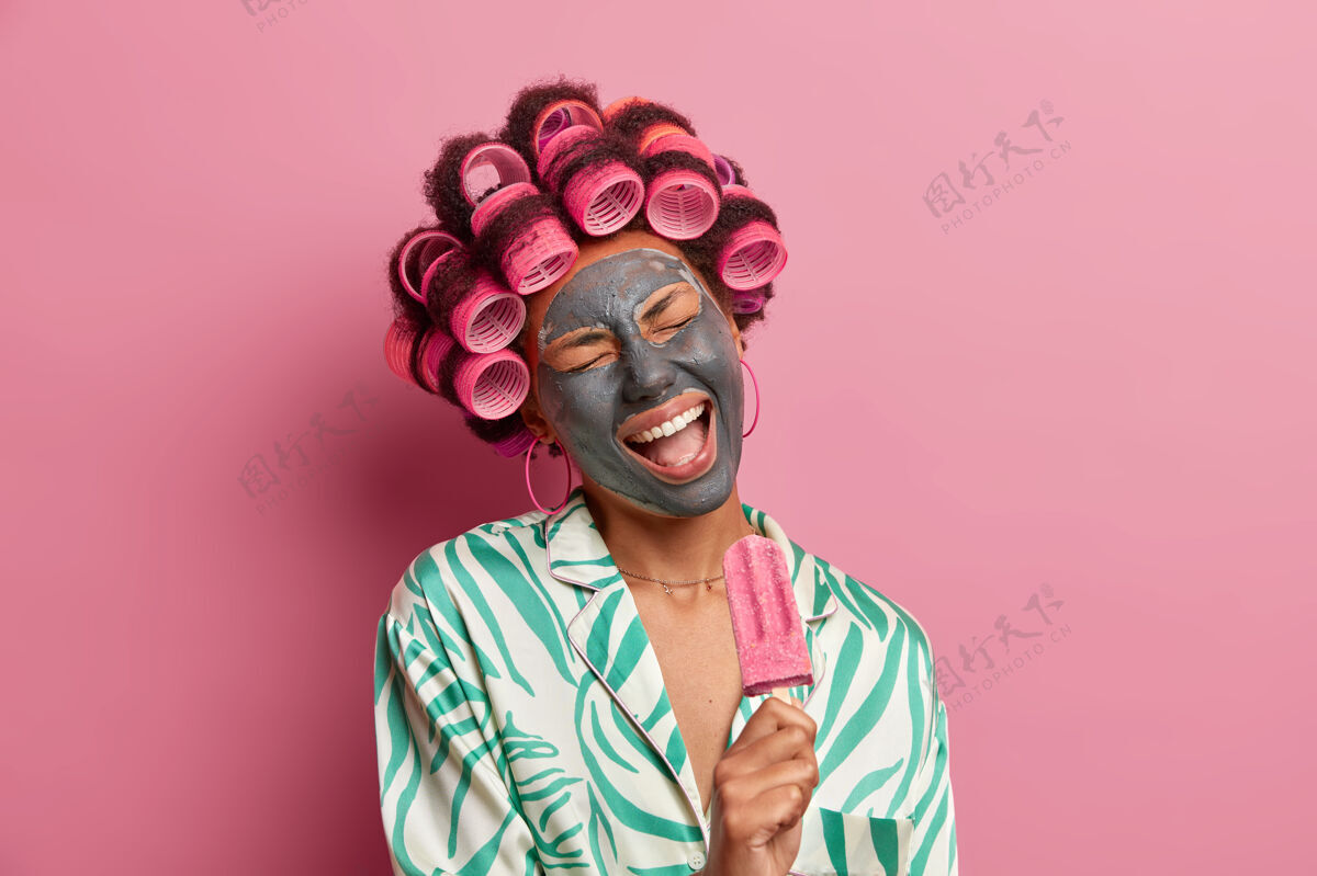 民族美丽的女士戴着面膜进行面部护理戴着卷发器隔离精力充沛年轻睡衣