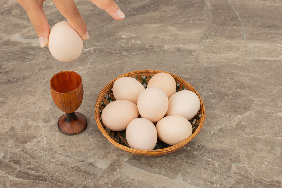木头手拿一个鸡蛋和一篮子白鸡蛋鸡蛋大理石贝壳
