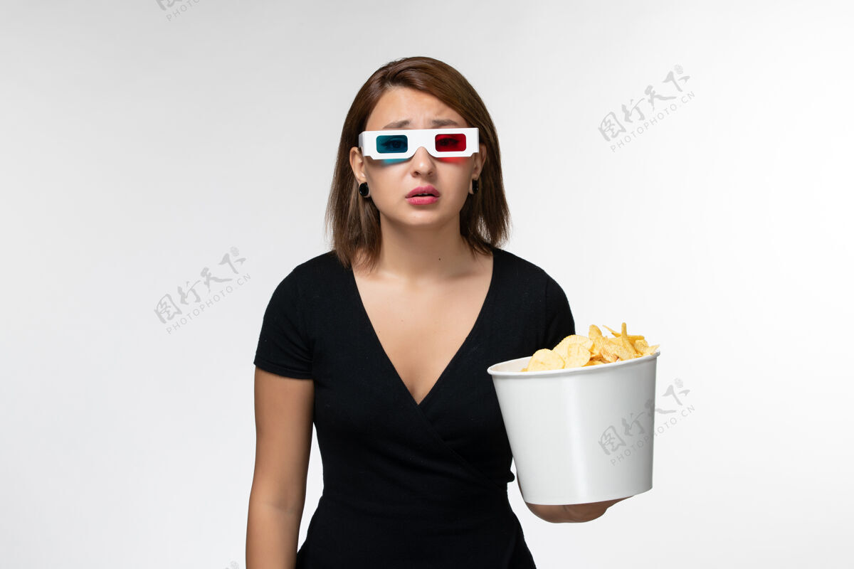 土豆正面图年轻女性戴着d型太阳镜拿着薯片 在白色表面看电影漂亮电影眼镜