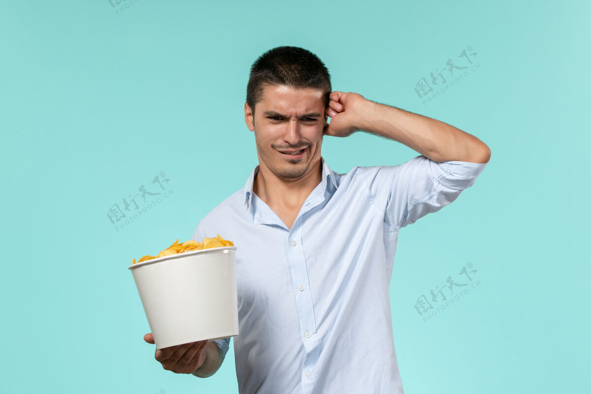 抱着正面图：年轻的男性拿着蓝面薯片的篮子孤独电影院电影