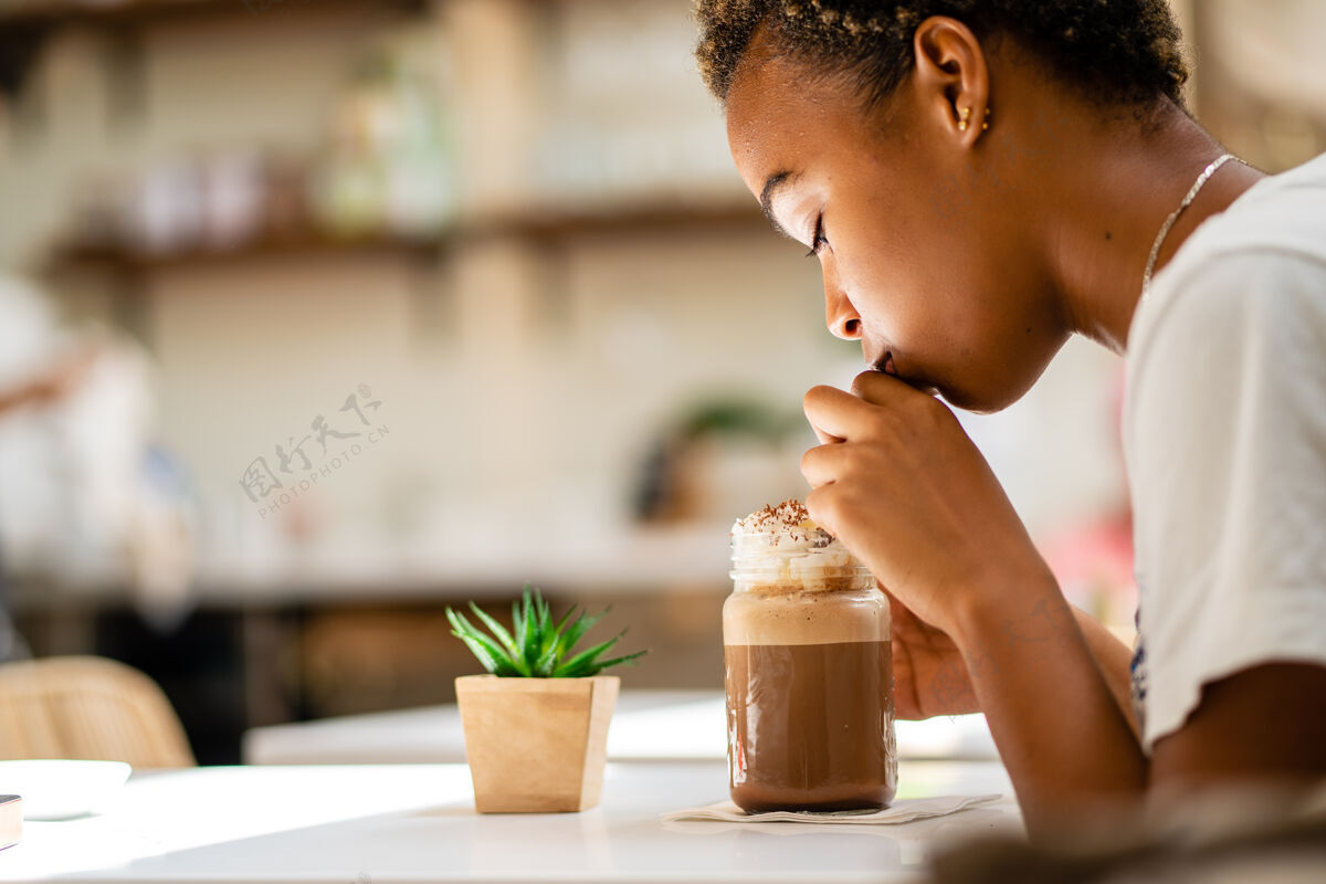 鸡尾酒一个非洲裔美国女性喝奶昔的浅焦镜头背景寒冷健康