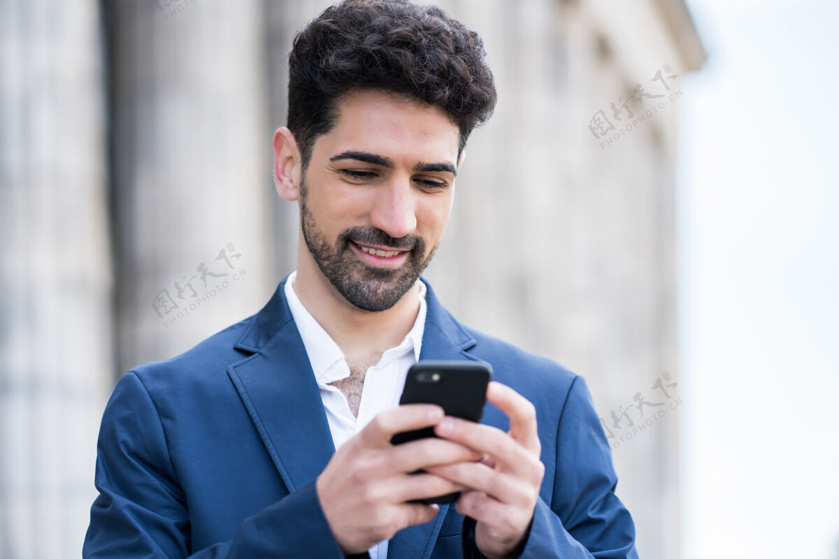男性一个商人站在街上使用手机的肖像商业和城市概念正面应用程序城市