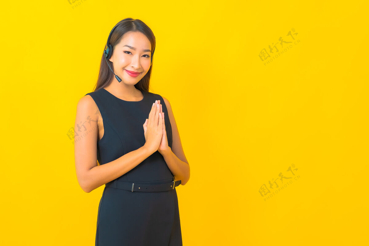 中心肖像美丽的年轻亚洲女商人与耳机呼叫中心客户关怀黄色背景员工耳机微笑