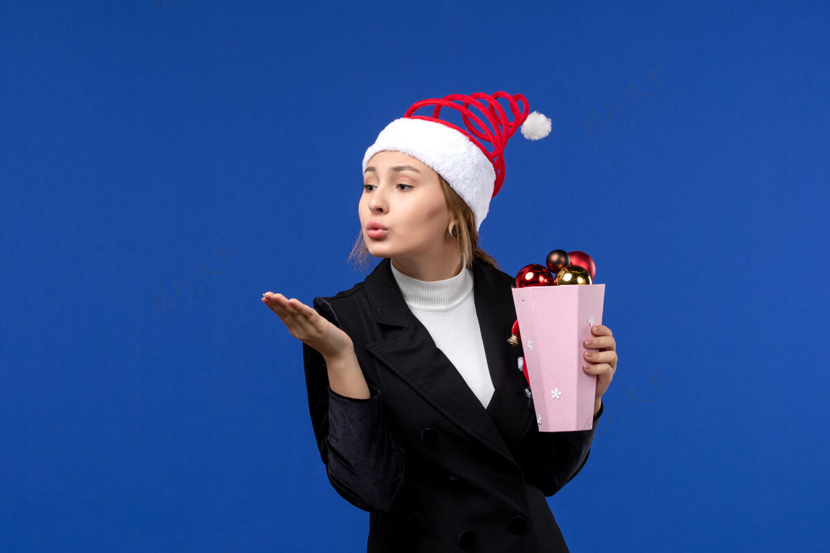 玩具正面图年轻女性带着蓝色墙壁上的圣诞树玩具色彩新年假期感慨正面经理执行