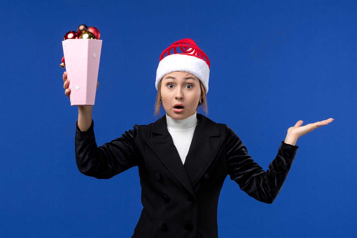 女人前视图美丽的女人拿着树玩具在蓝色墙上新年假期女人蓝色圣诞节火炬玩具